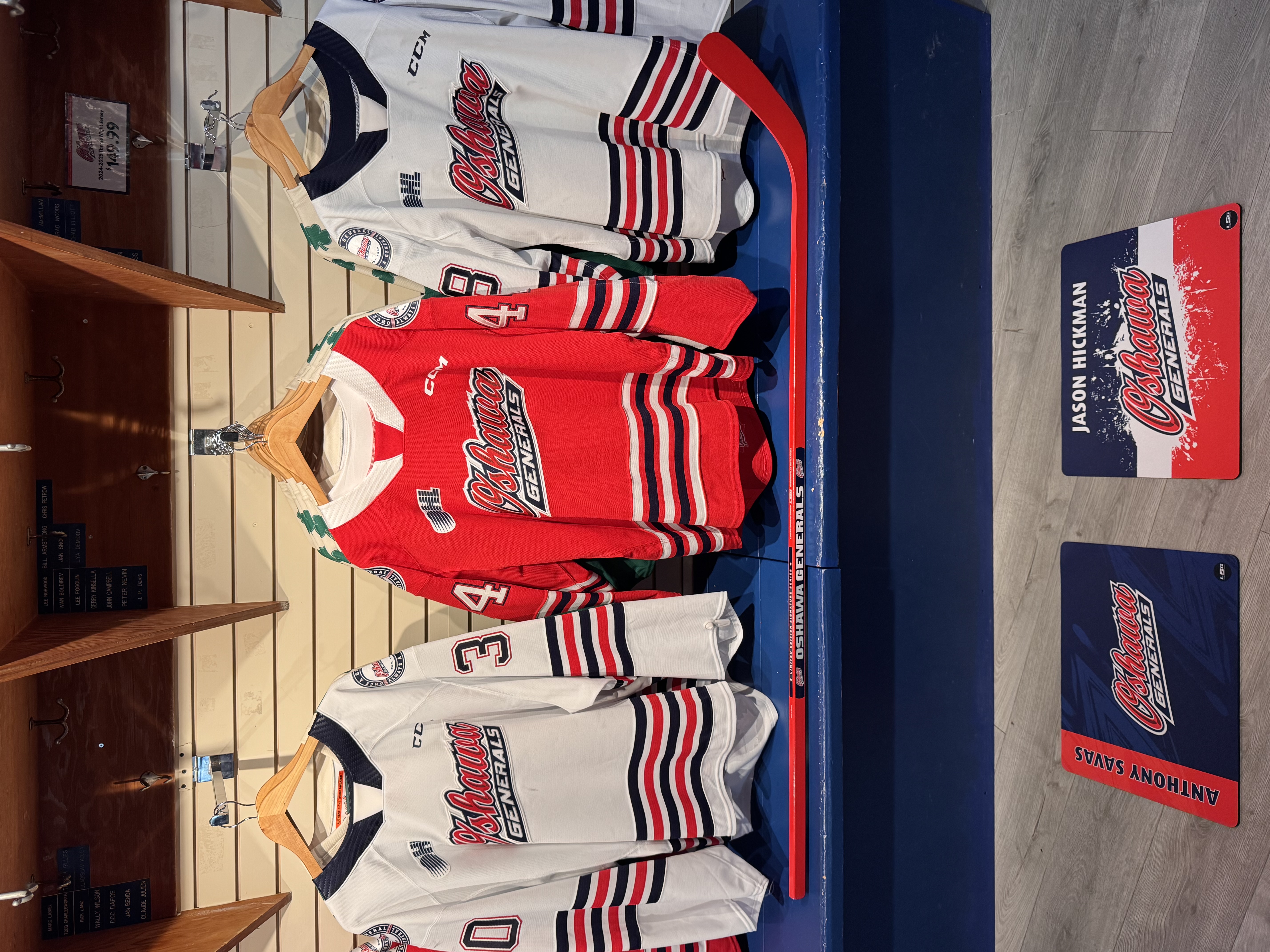 Oshawa Generals hockey jerseys on display with custom skate mats for Anthony Savas and Jason Hickman featuring team colors and logo